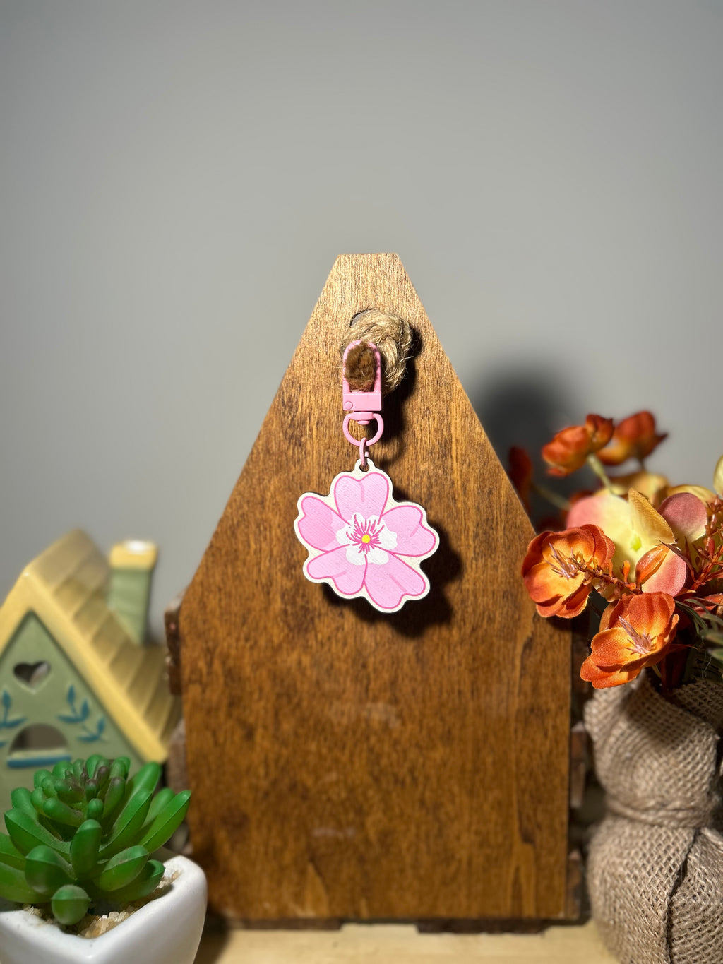 Pink blossom wooden keychain displayed hanging infront of a wooden display.